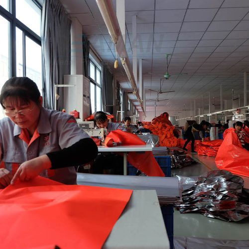 Life jacket production workshop with workers cutting and sewing fabric